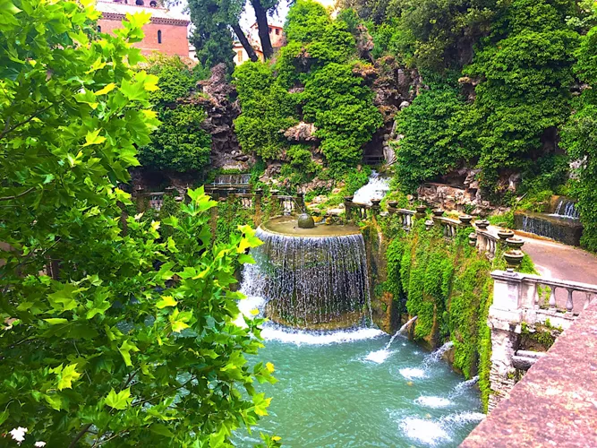 Ovalfontænen i Villa d'Este omgivet af grønt, med vandfaldet, der strømmer ned i det ovale bassin